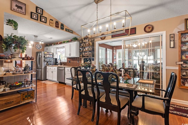 dining room with a textured ceiling, a healthy amount of sunlight, vaulted ceiling, and hardwood / wood-style flooring