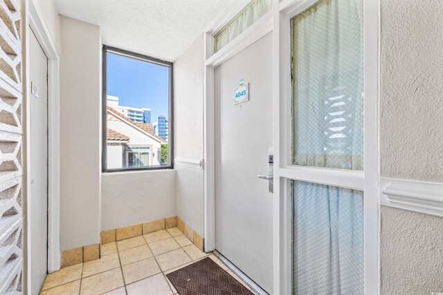 doorway to outside featuring light tile patterned flooring and a textured ceiling