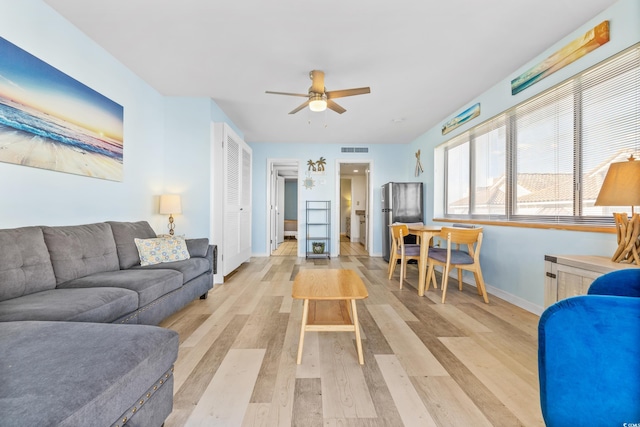 living area with a ceiling fan, light wood-style floors, visible vents, and baseboards