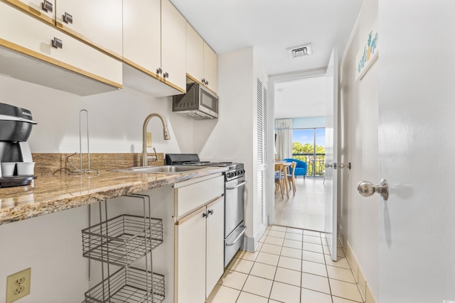 kitchen featuring light stone counters, visible vents, light tile patterned flooring, a sink, and appliances with stainless steel finishes