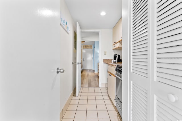 kitchen with light countertops, white cabinets, light tile patterned floors, and stainless steel gas range