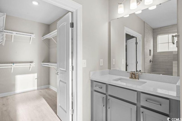 bathroom featuring hardwood / wood-style flooring, vanity, and a tile shower