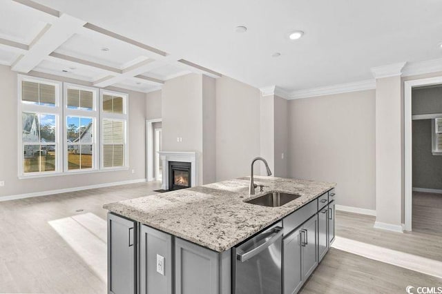 kitchen featuring gray cabinetry, light stone countertops, dishwasher, sink, and a kitchen island with sink