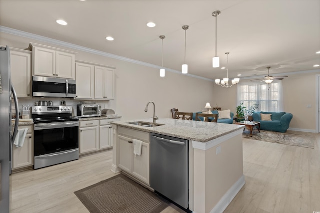 kitchen featuring appliances with stainless steel finishes, decorative light fixtures, sink, white cabinets, and light stone countertops