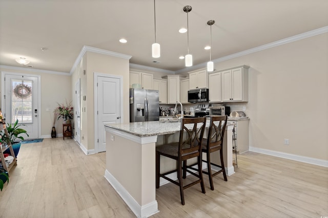 kitchen featuring light stone counters, decorative light fixtures, a center island with sink, ornamental molding, and stainless steel appliances