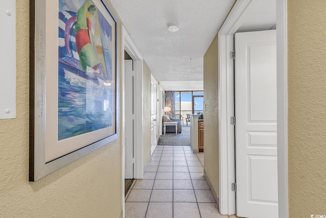 hall with a textured ceiling and light tile patterned floors