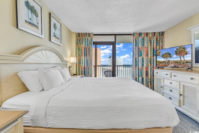 bedroom with multiple windows, access to outside, and a textured ceiling