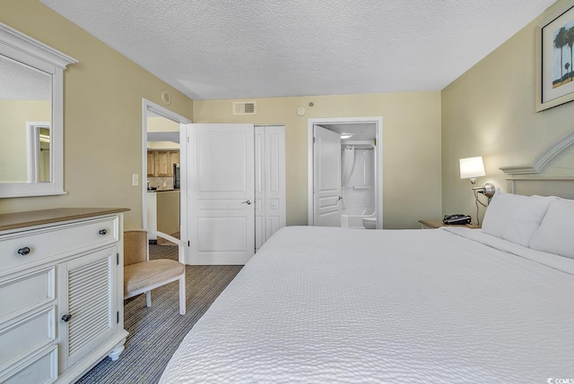 bedroom with a textured ceiling, ensuite bath, and dark hardwood / wood-style floors