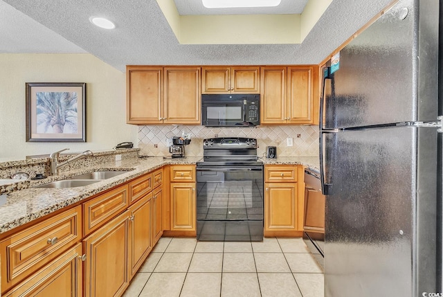 kitchen featuring a textured ceiling, black appliances, light tile patterned flooring, and sink