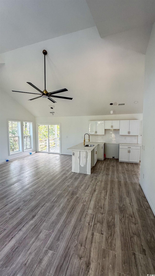 unfurnished living room featuring vaulted ceiling, ceiling fan, dark wood-type flooring, and sink