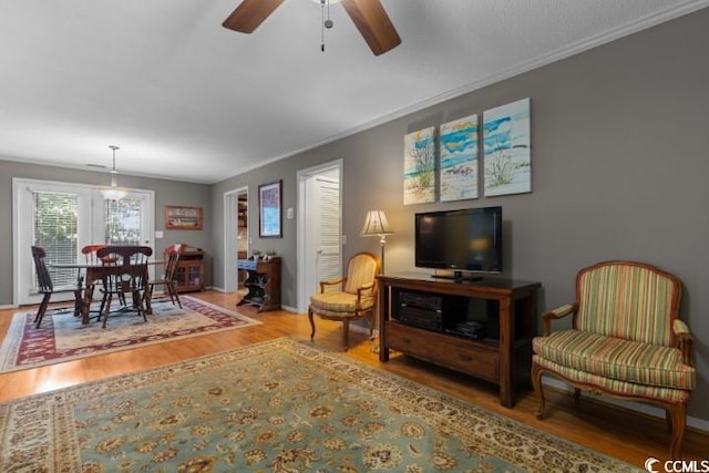 living room with hardwood / wood-style floors, ceiling fan, and crown molding