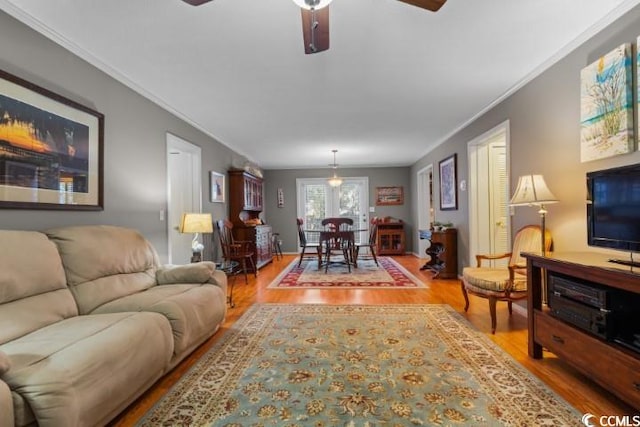 living room with ornamental molding, light hardwood / wood-style flooring, and ceiling fan