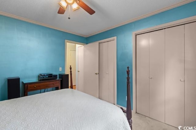 bedroom with light carpet, crown molding, multiple closets, and ceiling fan