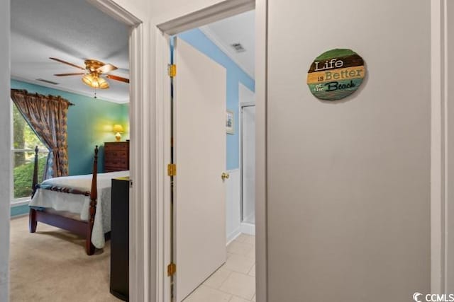 hallway with ornamental molding and light colored carpet