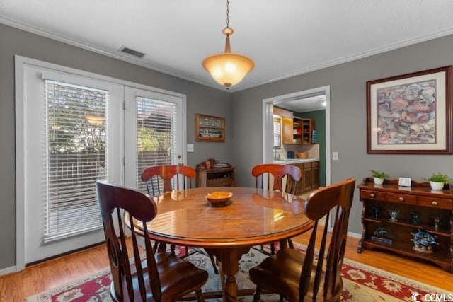 dining room with light hardwood / wood-style floors and crown molding