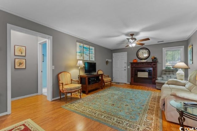 living room featuring ceiling fan, ornamental molding, and hardwood / wood-style flooring