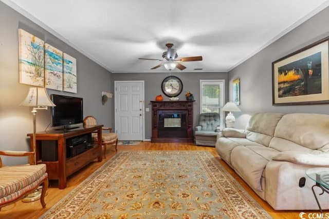 living room with crown molding, ceiling fan, and light hardwood / wood-style floors