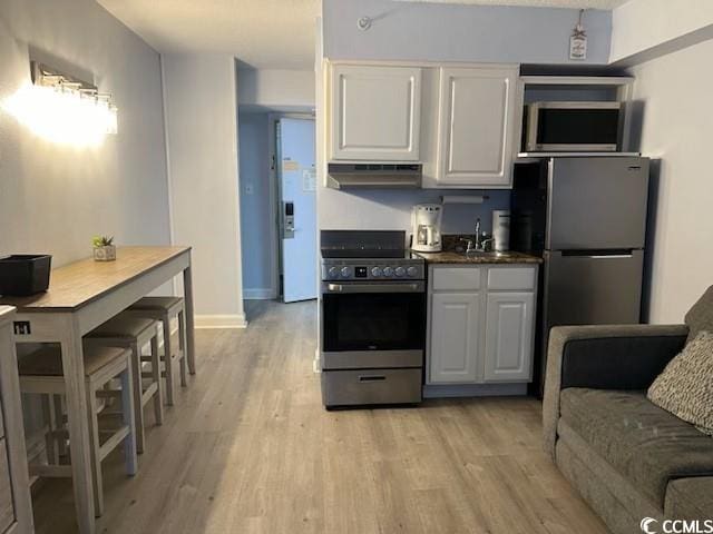 kitchen with white cabinets, stainless steel appliances, light wood-type flooring, and exhaust hood