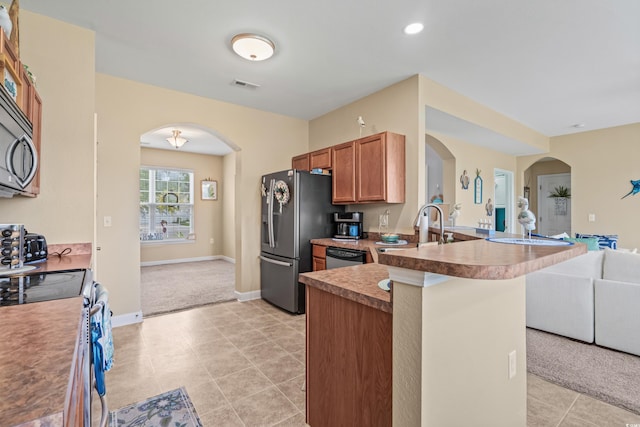 kitchen with sink, appliances with stainless steel finishes, kitchen peninsula, and light colored carpet