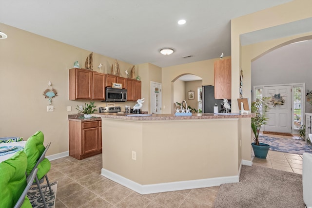 kitchen with appliances with stainless steel finishes, kitchen peninsula, sink, and light tile patterned floors