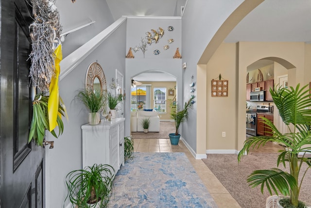 foyer featuring ceiling fan, high vaulted ceiling, and light tile patterned floors