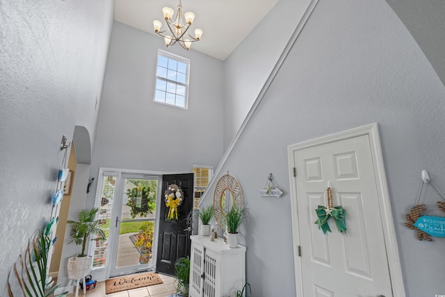 tiled foyer featuring high vaulted ceiling and an inviting chandelier