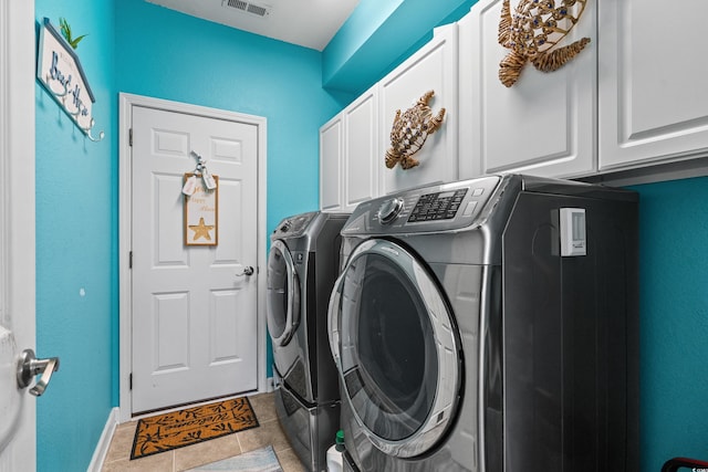 clothes washing area with cabinets, separate washer and dryer, and light tile patterned floors