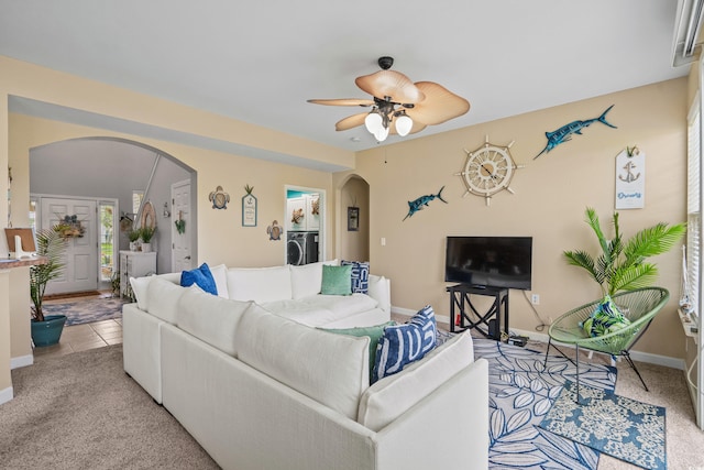 living room featuring washer / dryer, light colored carpet, and ceiling fan