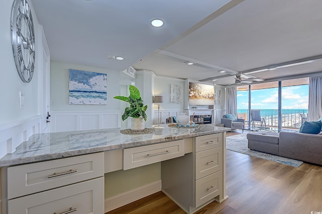 kitchen featuring built in desk, light hardwood / wood-style floors, white cabinets, light stone countertops, and ceiling fan