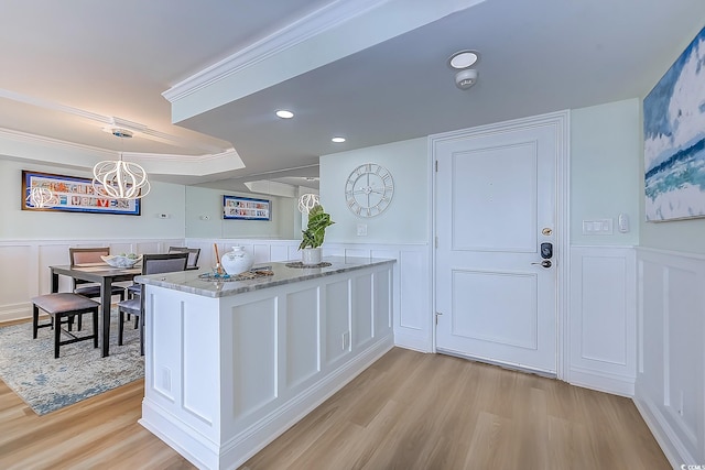 kitchen with light hardwood / wood-style flooring, hanging light fixtures, kitchen peninsula, and white cabinetry