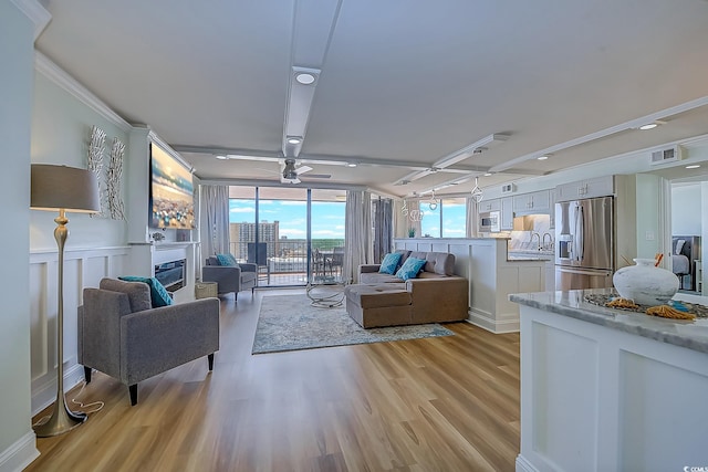 living room featuring crown molding, ceiling fan, light hardwood / wood-style flooring, and sink