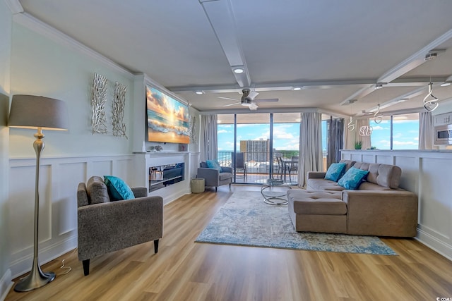 living room with ornamental molding, light wood-type flooring, beam ceiling, and ceiling fan