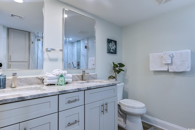 bathroom featuring vanity, a shower with shower door, and toilet