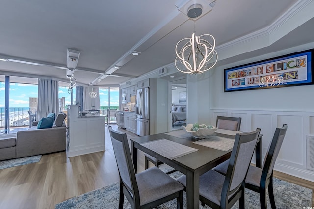 dining area featuring light wood-type flooring, a chandelier, ornamental molding, and a wealth of natural light