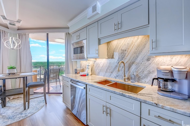 kitchen featuring appliances with stainless steel finishes, sink, light hardwood / wood-style flooring, and light stone counters