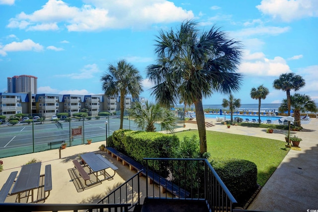 exterior space featuring tennis court, a water view, and a yard