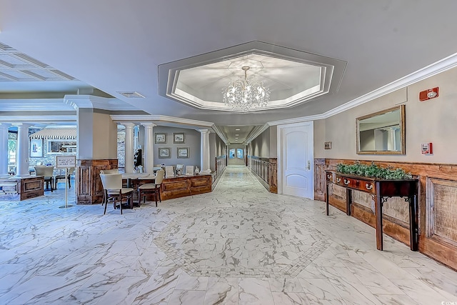 entryway with decorative columns, ornamental molding, and an inviting chandelier