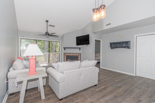 living room with ceiling fan with notable chandelier, high vaulted ceiling, hardwood / wood-style floors, and a tile fireplace