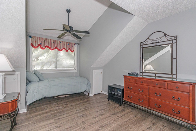 bedroom with a textured ceiling, ceiling fan, hardwood / wood-style floors, and vaulted ceiling