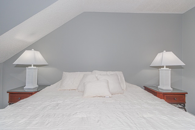 bedroom featuring vaulted ceiling and a textured ceiling