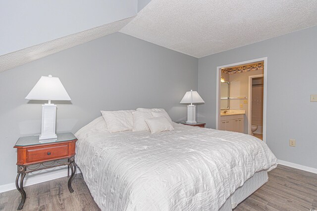 bedroom with lofted ceiling, ensuite bath, and hardwood / wood-style flooring