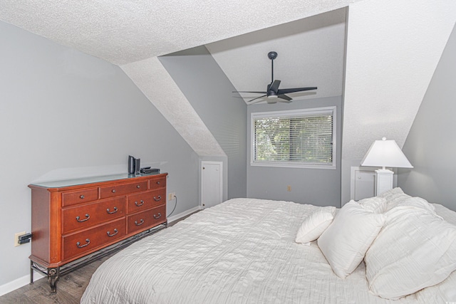 bedroom with vaulted ceiling, a textured ceiling, wood-type flooring, and ceiling fan