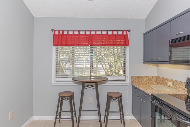 kitchen featuring black appliances, a wealth of natural light, light tile patterned floors, and a textured ceiling