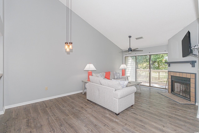 living room featuring high vaulted ceiling, a tile fireplace, hardwood / wood-style flooring, and ceiling fan