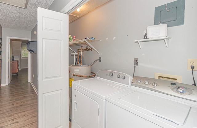 laundry area with a textured ceiling, hardwood / wood-style floors, electric panel, separate washer and dryer, and water heater