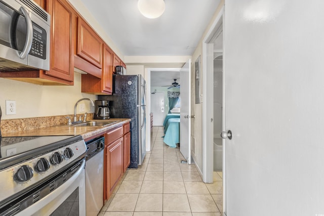 kitchen featuring stainless steel appliances, sink, ceiling fan, and light tile patterned flooring