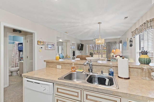 kitchen featuring light countertops, open floor plan, a healthy amount of sunlight, a sink, and dishwasher