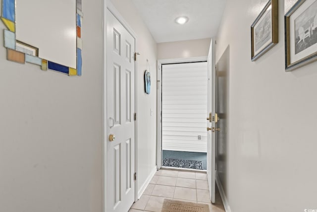 doorway to outside with light tile patterned floors and baseboards