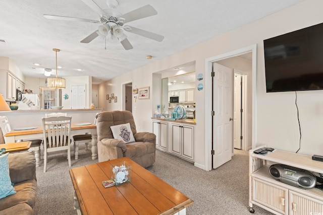 carpeted living room with ceiling fan with notable chandelier