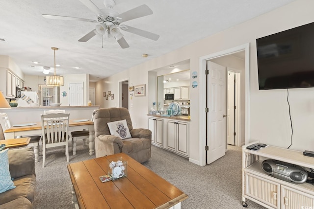 living room with visible vents, ceiling fan with notable chandelier, and light colored carpet